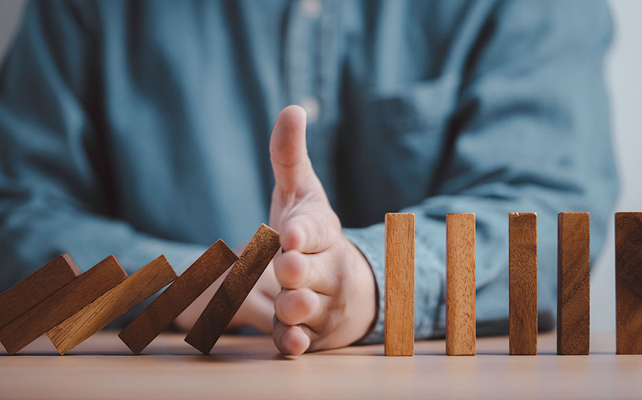 Prevention - hand stopping the domino from falling